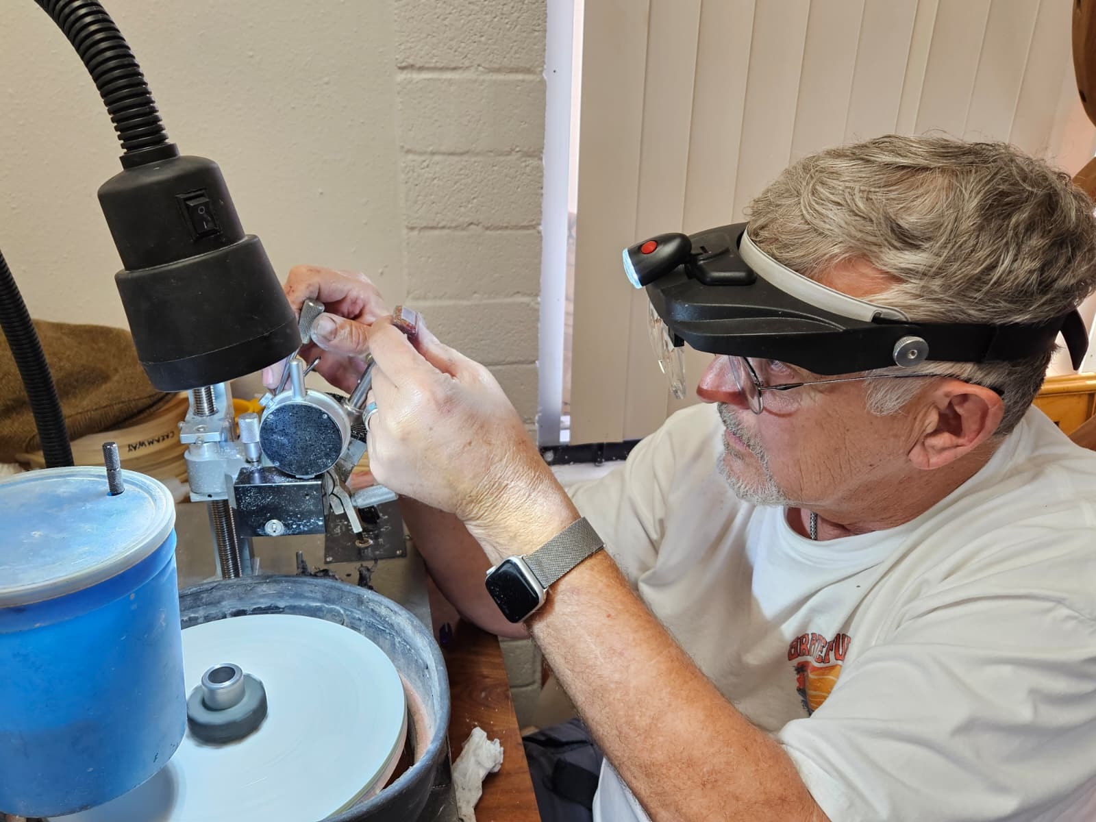 Les at the faceting machine, a stone on the dop stick under the lamp.